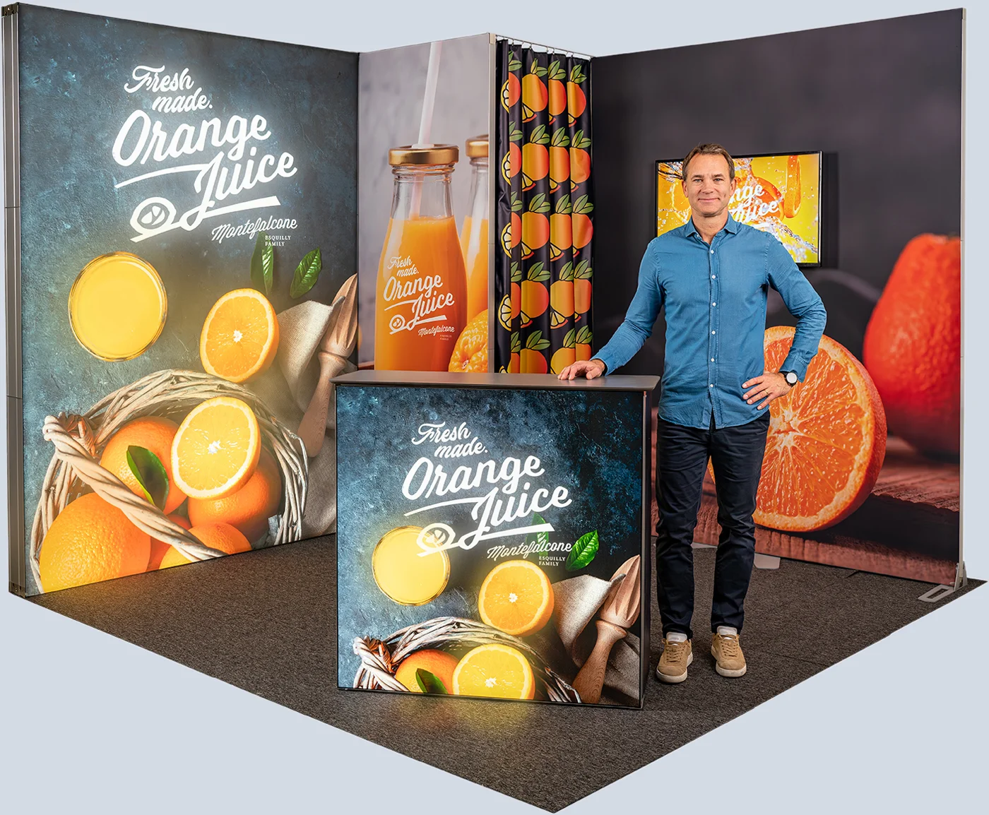 Messestand mit Orangensaft-Werbung und Mann daneben.